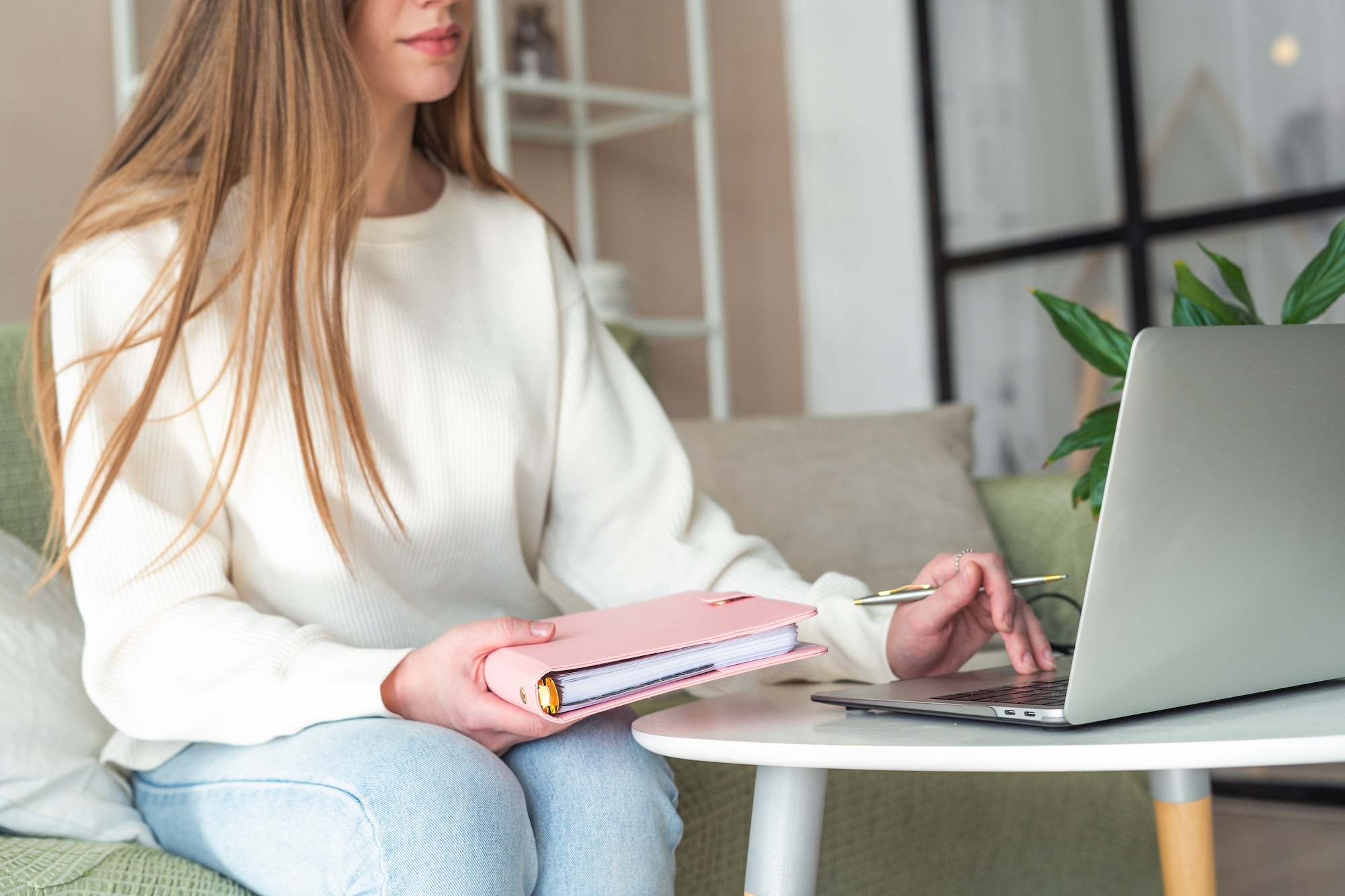 Woman typing on laptop notebook. Holding notepad, working home office online with technology